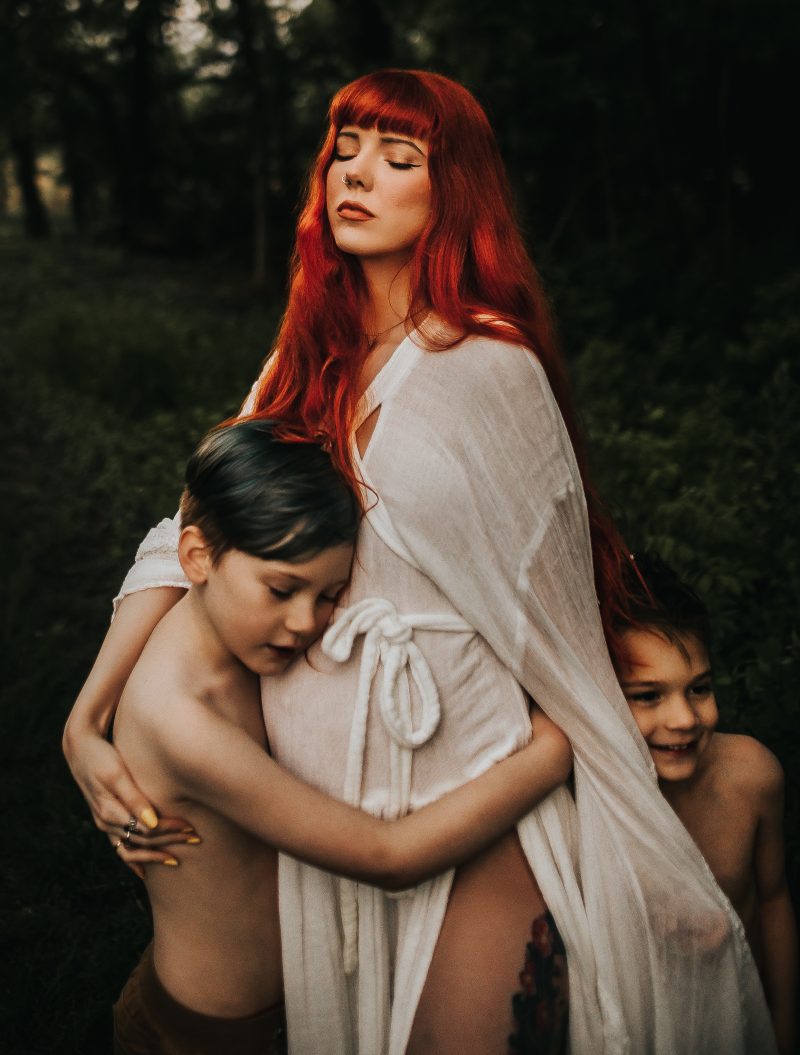 a beautiful red haired mother with family in a green field