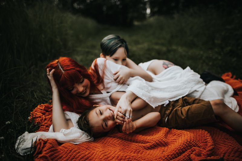 a beautiful red haired mother with family in a green field